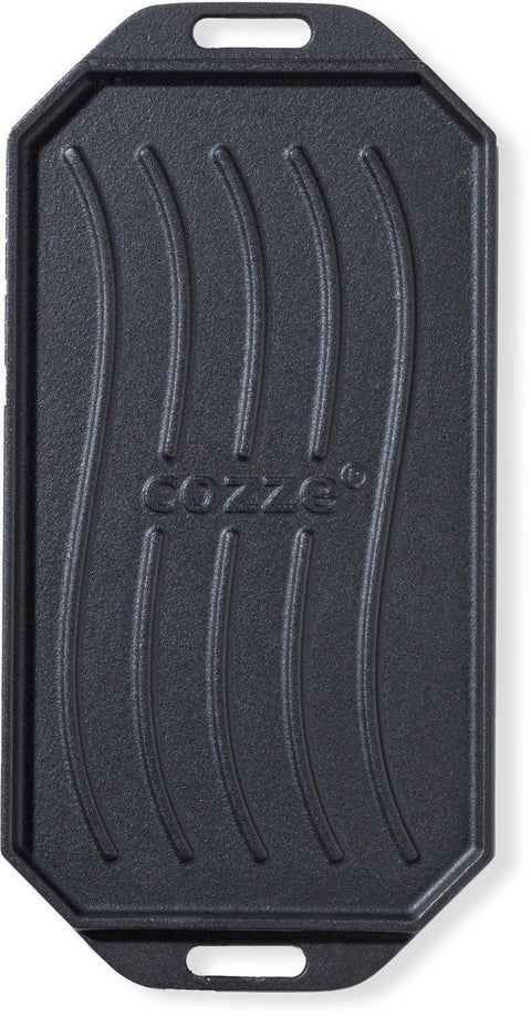 Die Cozze Gusseisen-Wendepfanne mit Untersetzer 165x330mm ist eine schwarze rechteckige Grillplatte mit Griffen, erhöhten Linien und abgerundeten Ecken. In der Mitte ist der Schriftzug "COZZE" eingeprägt - perfekt für Pizzaofen oder als Gusseisen-Wendepfanne.