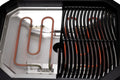 Nahaufnahme des Cozze E-500 Grills von Cozze: Seine Zwei-Zonen-Technik zeigt links ein rot leuchtendes Heizelement und rechts einen schwarzen Grillrost - perfekt zum Grillen auf dem Balkon. Elektrisch betrieben (230V, CH-Stecker).