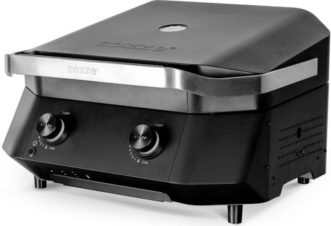 Der Cozze G-500 Grill, Gas 50mbar - CH-Regler hat ein schwarzes Design mit Edelstahlfront, zwei Bedienknöpfe, einen geschlossenen Deckel, seitliche Lüftungslöcher und vier kurze Beine - ideal für Ihre Terrasse.