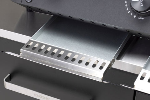 Nahaufnahme einer Metallabtropfschale, die teilweise unter der Cozze G-800 Plancha mit Deckel, Gas 50mbar - CH-Regler von Cozze herausgeschoben wurde, mit den geschlitzten Kanten und einem Teil des Bedienfelds darüber.
