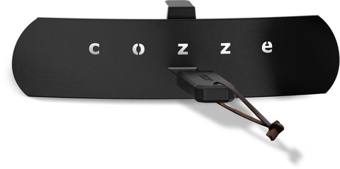 Ein schwarzes Metallschild mit dem Schriftzug "cozze" in Weiß und ein schlanker USB-Stick mit braunem Kabel erinnern an das moderne Design des Cozze Pizzaofen Rotate - Black Edition [13 Zoll] von Cozze.