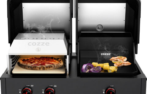 Ein Cozze Grill Quattro 900, Gas, 50mbar - CH-Regler, wird gezeigt, wie auf der einen Seite Pizza gebacken wird, während auf der anderen Seite Garnelen, Mais und rote Zwiebeln gegrillt werden. Beide Deckel sind geöffnet, so dass das Grillgut sichtbar ist und von beiden Seiten Rauch aufsteigt.