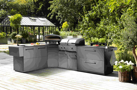 Eine moderne Außenküche mit schlichten grauen Schränken, Gasgrill, Pizzaofen und Vorbereitungszone mit Cozze Elements Abfalleimer von Cozze auf einer Holzterrasse, umgeben von Grünpflanzen und einem Glasgewächshaus im Hintergrund.