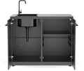 Das Cozze Elements Outdoor-Küche Spülmodul mit Tischplatte [110 cm] verfügt über einen schwarzen Schrank mit offenen Türen, ein Unterbauspülbecken, freiliegende Rohrleitungen, eine Edelstahl-Tischplatte und einen modernen schwarzen Wasserhahn - ideal für stilvolle Outdoor-Küchen.