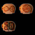 Blick von oben auf drei kleine Pizzaöfen - darunter ein Gozney Dome Gen 2 Pizzaofen von Gozney mit Hybrid Brennstoffsystem. Zwei Öfen backen Pizza, während der dritte in dieser Outdoor-Küche gebratenes Gemüse, Garnelen aus der Pfanne und Fisch mit Zitrone zubereitet.