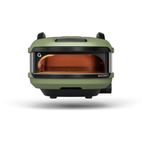 Der Gozney Tread Gas Pizzaofen Olive (Mobil) von pazzalovers.com ist ein kompakter, moderner Ofen für Ihre Outdoor-Küche. Er verfügt über eine elegante Frontöffnung mit orangefarbenem Innenleben und „GOZNEY“-Etikett an der Unterseite, das einen eleganten Kontrast zum schlichten schwarzen Hintergrund bildet.