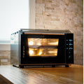 Der Effeuno Pizzaofen EffeUno P234H PRO 509°C ist ideal für perfekte neapolitanische Pizzen und besticht durch moderne digitale Bedienelemente und ein elegantes Edelstahl-Finish. Er steht elegant auf einer Holzoberfläche und das warme Licht seiner Innenbeleuchtung harmoniert perfekt mit einer Steinfliesenwand und einem Fenster.