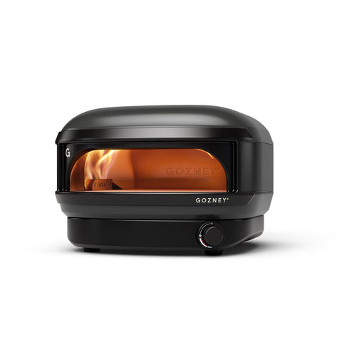 Der Gozney Arc Lite Gas Pizzaofen ist ein schwarzer, gasbetriebener Ofen mit einer Glasfront, die eine orangefarbene Flamme zeigt. Er hat eine abgerundete Oberseite, einen Bedienknopf unten rechts und erreicht bis zu 500 °C.