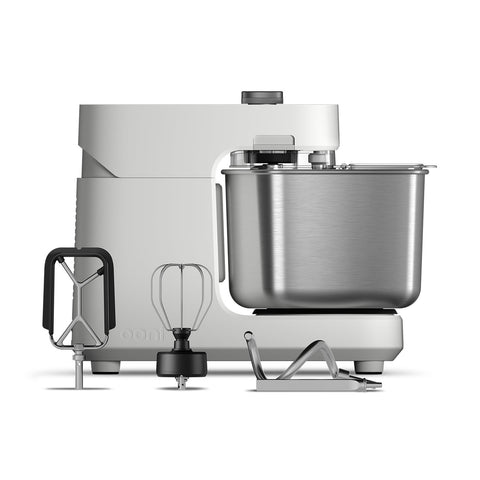 Wir präsentieren die Ooni Halo Pro Spiral-Knetmaschine von Ooni, eine elegante Küchenmaschine mit Spiral-Knettechnologie. Sie verfügt über eine Edelstahlschüssel, ein hellgraues Gehäuse und enthält einen Rührer, Schneebesen und Knethaken – ideal, um jedes Mal einen perfekten Pizzateig zuzubereiten.