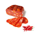 Ein Block Madeo Salami Spianata am Stuck (Schiacciata) 250G mit drei dünnen Scheiben und roten Chilischoten ist auf einem weißen Hintergrund abgebildet.