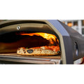 Eine Nahaufnahme einer Pizza, die im Ooni Karu 2 Outdoor-Pizzaofen von Ooni gebacken wird, mit sichtbaren Flammen im Hintergrund und einer leicht verkohlten Kruste.