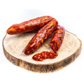 Eine Auswahl mehrerer Salsiccia Salami BIO (Scharf), arrangiert auf einem Holzbrett, mit zwei kleinen Salamischeiben im Vordergrund. Die Madeo-Salami hat eine satte, tiefrotbraune Farbe mit sichtbarer Fettmarmorierung, die an pikantes, gepökeltes Fleisch erinnert. Perfekt für alle, die Fleischspezialitäten lieben.