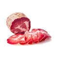 Ein dickes Stück von Madeos Capocollo Calabrese Mild (Coppa) – am Stück 700 g, mit einem marmorierten Muster aus magerem und fettem Fleisch, teilweise in dünne, zarte Stücke geschnitten, die vorn angeordnet sind. Die Scheiben weisen eine leuchtend rote Farbe mit weißen Streifen auf, die an traditionelle mediterrane Vorspeisen erinnern, auf weißem Hintergrund.