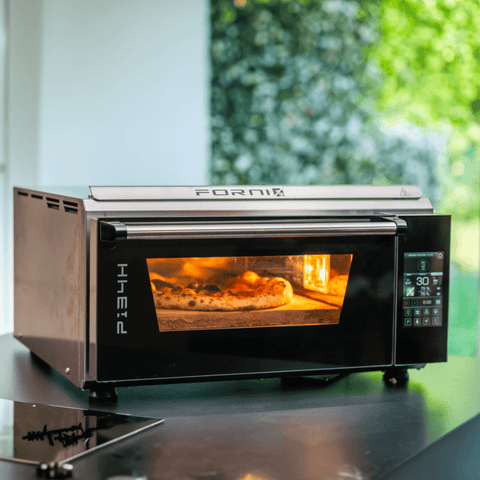 Der Effeuno Pizzaofen P134H 509°C Evolution mit Biscotto Pizzastein, ausgestattet mit einem digitalen Bedienfeld und PID-Temperaturregelung, backt eine Pizza mit geschmolzenem Käse und Belag. Die Innenbeleuchtung des Ofens beleuchtet die neapolitanische Pizzaqualität, während im Hintergrund durch ein Fenster üppiges Grün sichtbar ist.