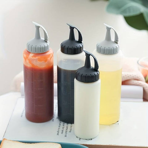 Auf einer weißen Fläche sind vier Dosierflaschen (350 ML) von Pizzalovers mit Klappverschluss angeordnet. Die Flaschen aus lebensmittelechtem Kunststoff enthalten unterschiedliche Soßen: eine rote, eine dunkelbraune, eine weiße und eine gelbe. Sie sind unterschiedlich groß, wobei sich hinten zwei größere und vorne zwei kleinere befinden.