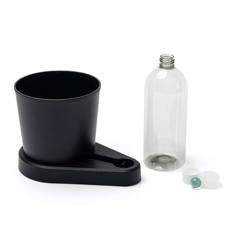Der Greevi Kräuterheld selbstbewässernder Kräuter-Pflanztopf sitzt neben einer klaren, leeren Flasche mit weißem Deckel und kleiner grüner Kugel - ideal für frische Kräuter in Ihrer Küche.